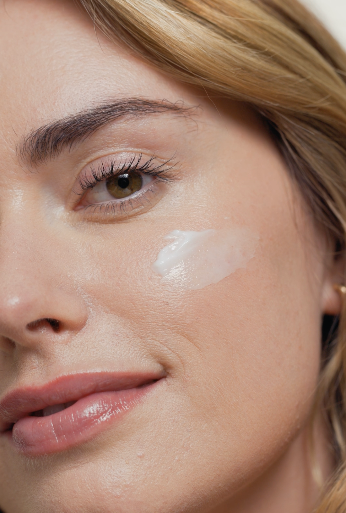 Close-up of a woman's face with a focus on her cheek, showing a light makeup application.